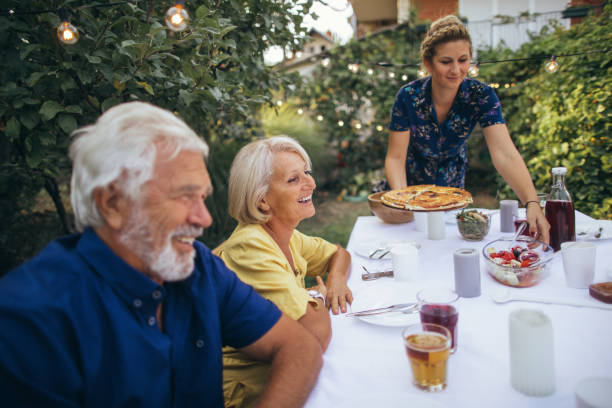 pizza being served to senior couple enjoying dinner at an outdoor table